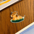 Sticker of a cartoon character on a wooden surface with books in the background