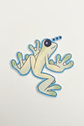 Cartoon frog sticker on a wooden surface