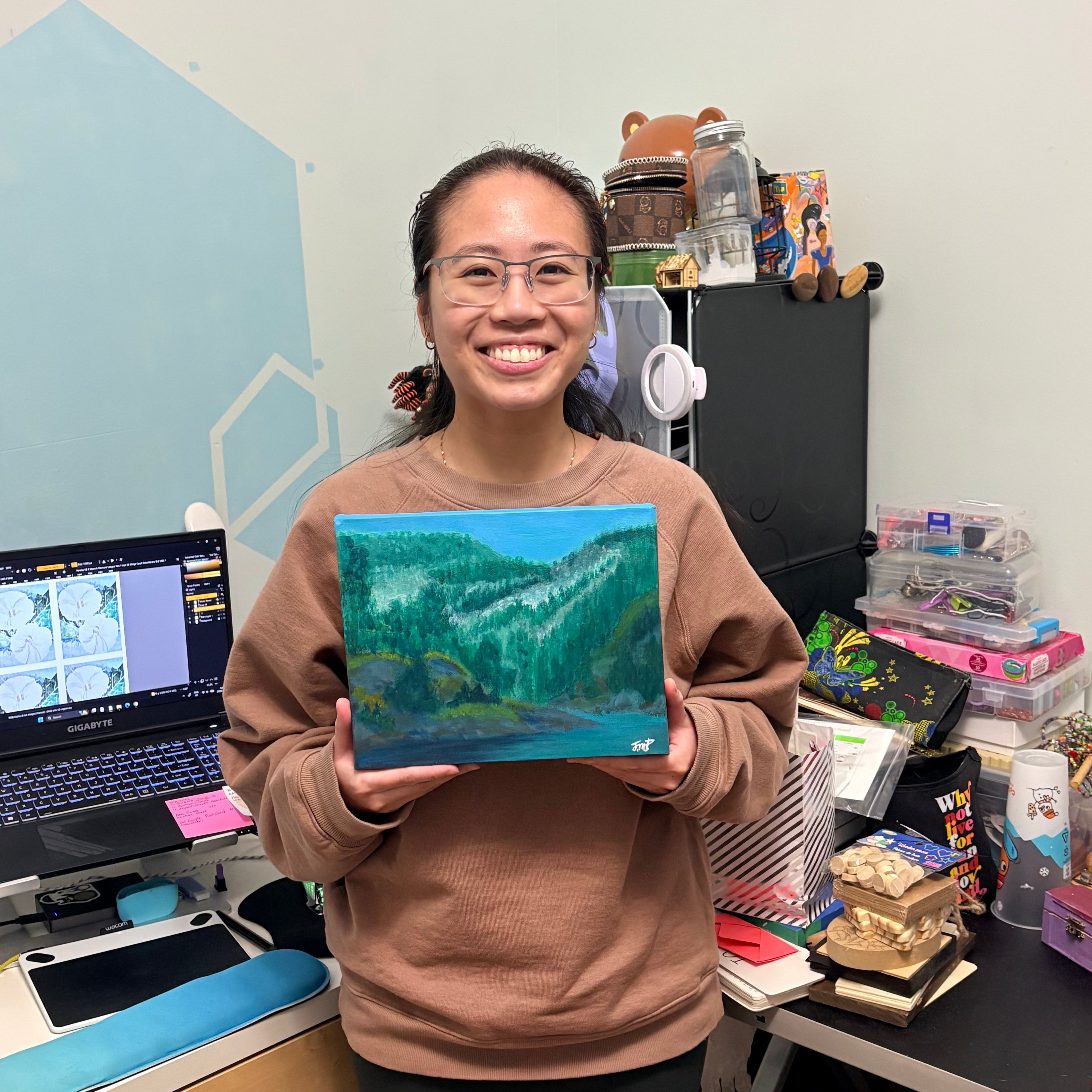 Jessie holding a blue and green patterned object in a cluttered room.