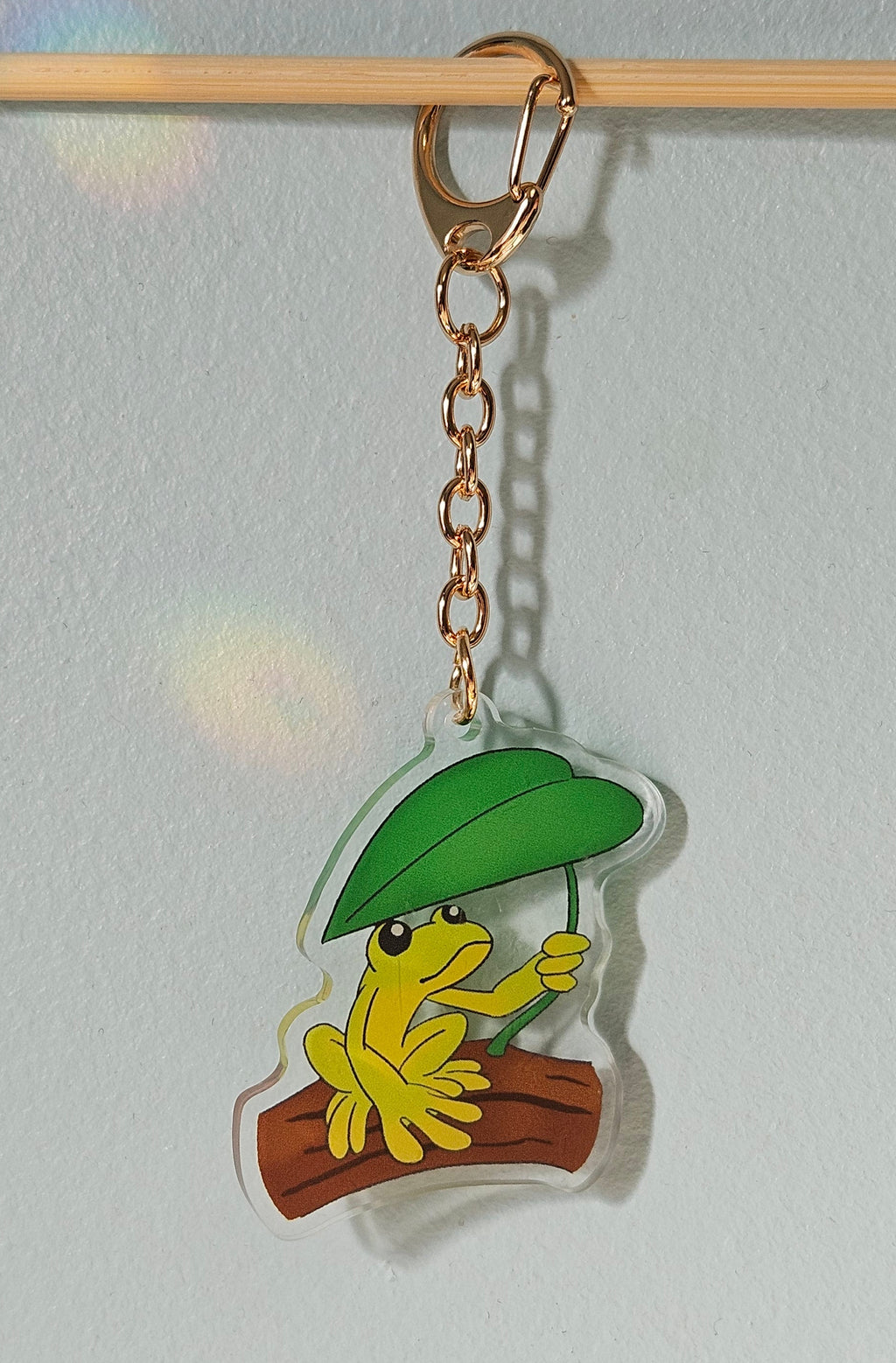 Keychain with a frog on a leaf design on a light gray background