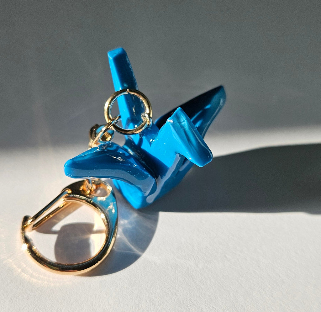 Blue polymer clay crane keychain with a gold D-clasp on a white background