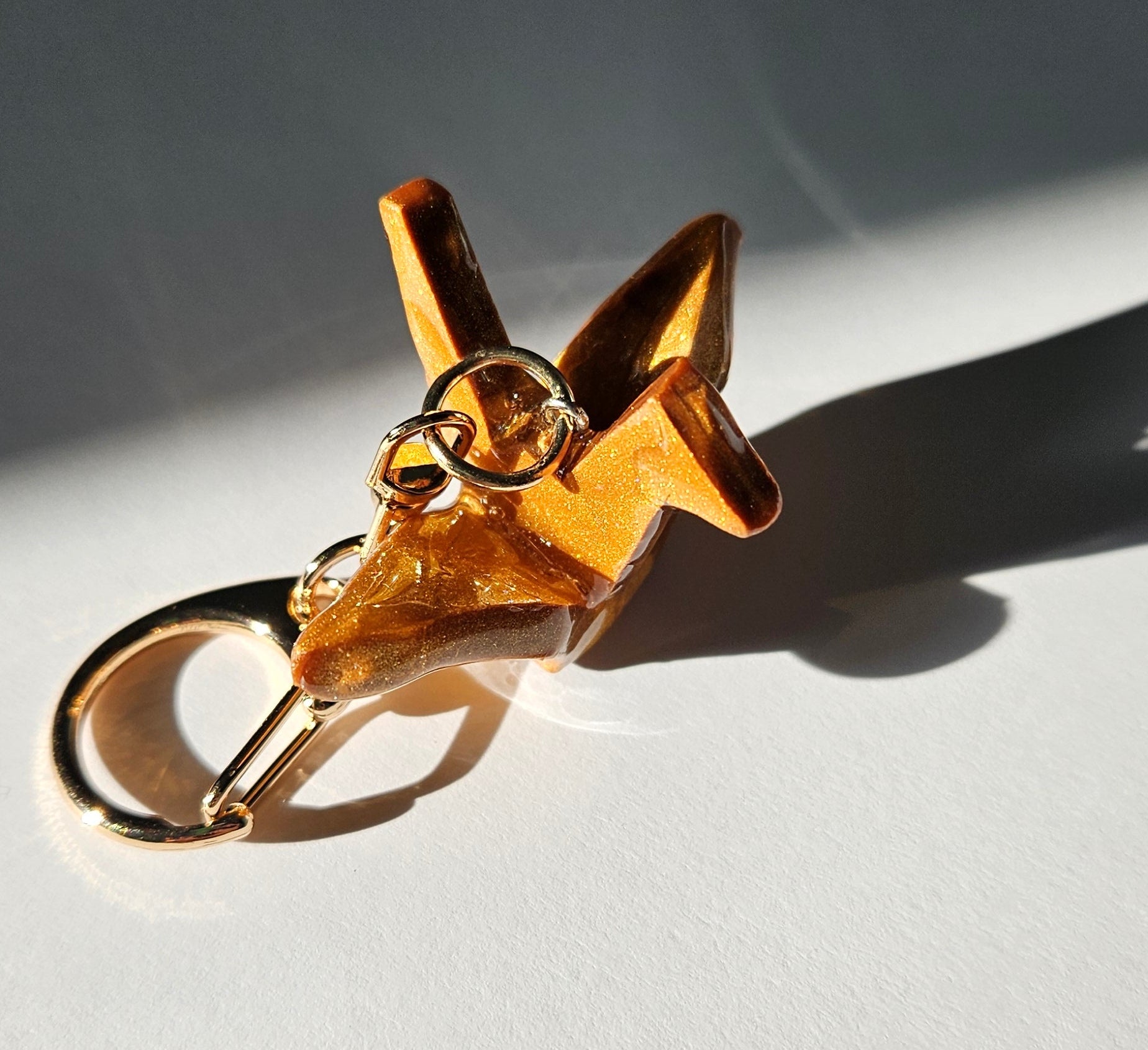 Gold polymer clay crane keychain on a white background