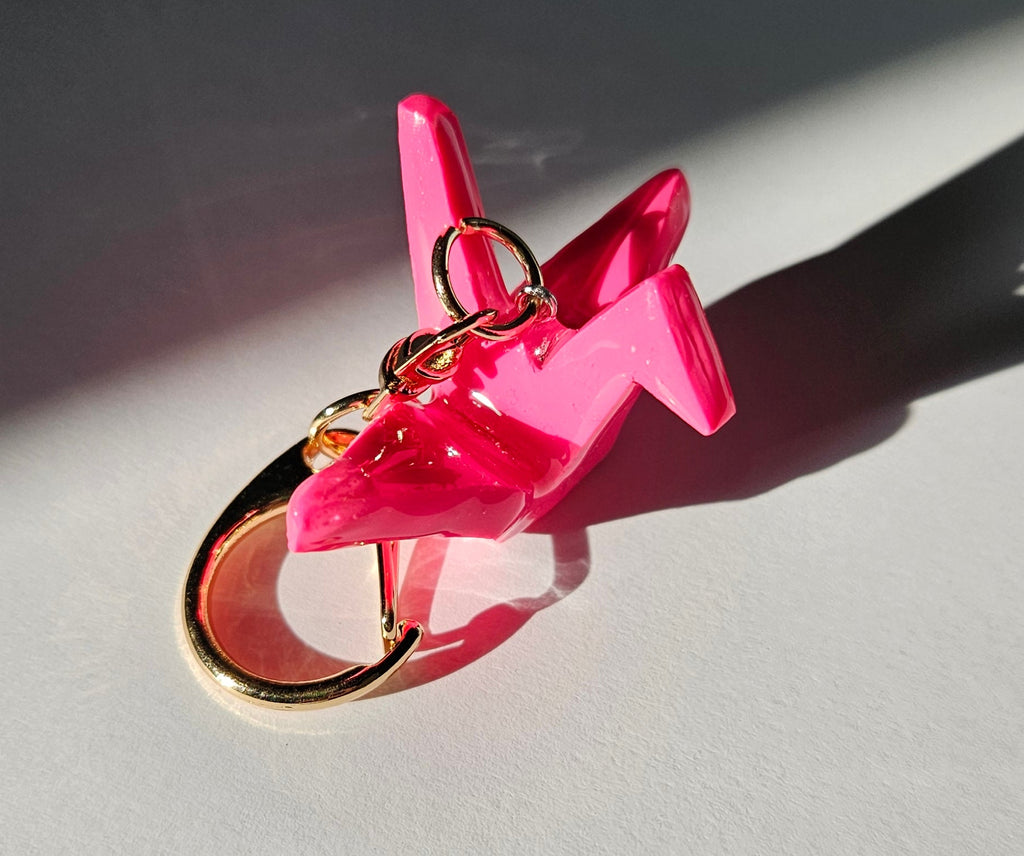 Pink polymer clay crane keychain with a gold D-clasp on a white background