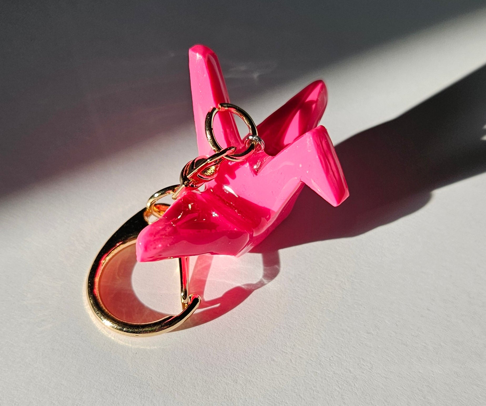 Pink polymer clay crane keychain with a gold D-clasp on a white background