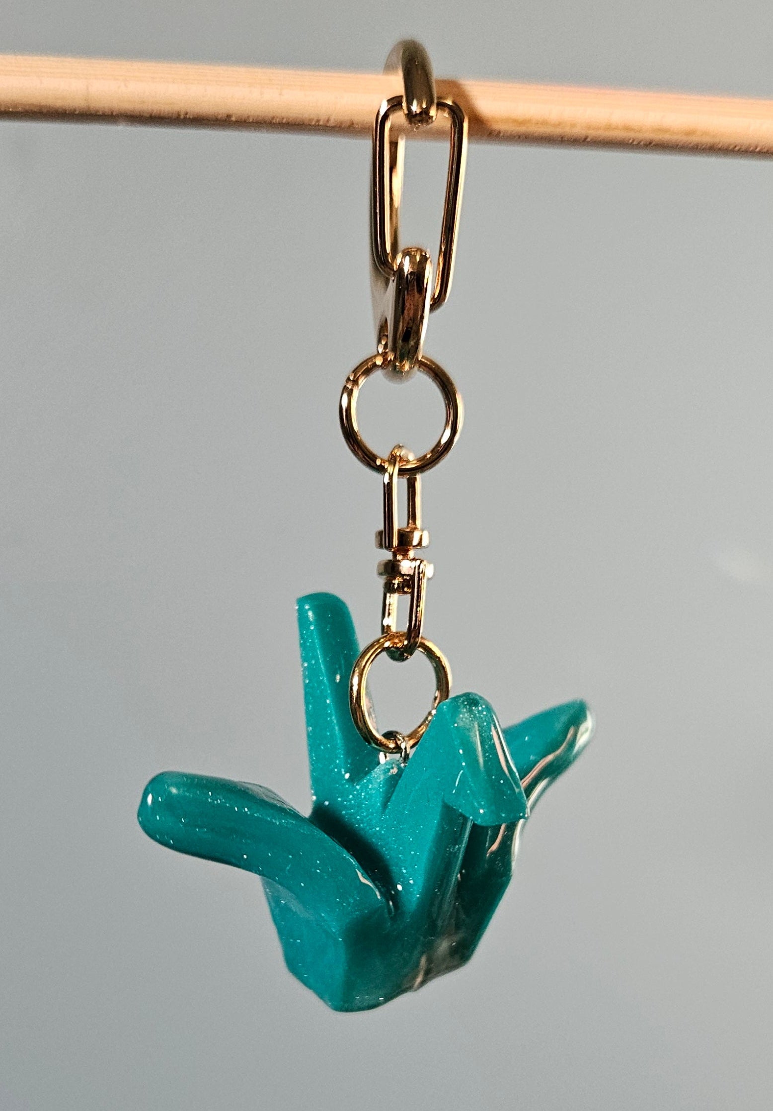 Teal keychain charm on a gray background